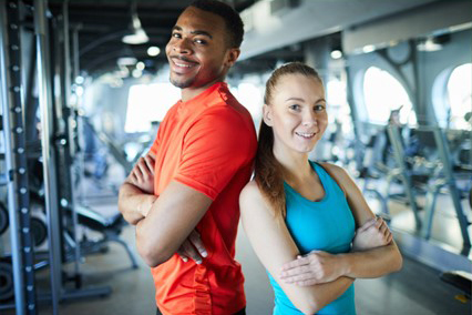 Two happy teenagers posing in a gym.